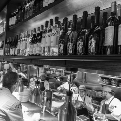 Black and white photo of activity on the kitchen line at Valentina's restaurant at Bridge Park in Dublin, Ohio.
