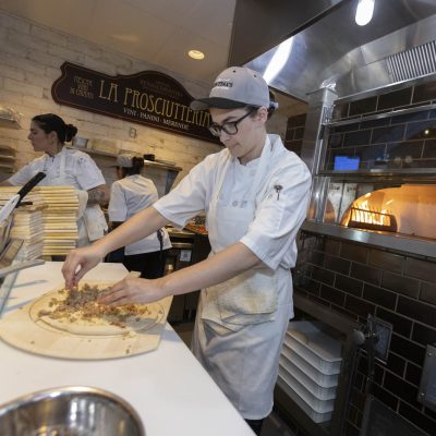 Chef creating pizza in front of wood-fired oven in the kitchen at Valentina's restaurant in Dublin, Ohio at Bridge Park.