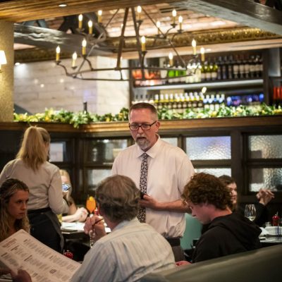 A server at Valentina's takes the orders of three guests