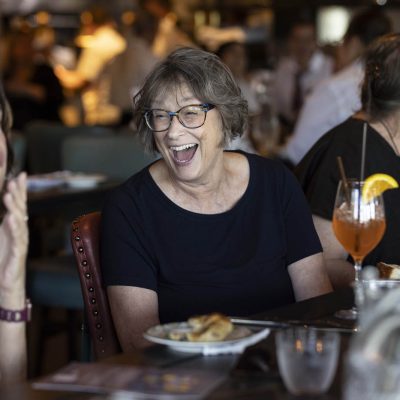 Woman laughing with friend at her table at Valentina's restaurant in Dublin, Ohio at Bridge Park.